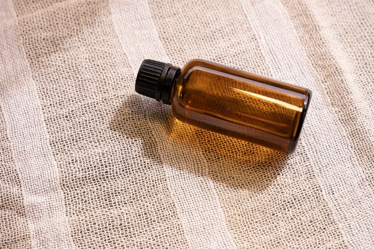 Flacon d'huile en verre brun couché sur une nappe de lin rayée