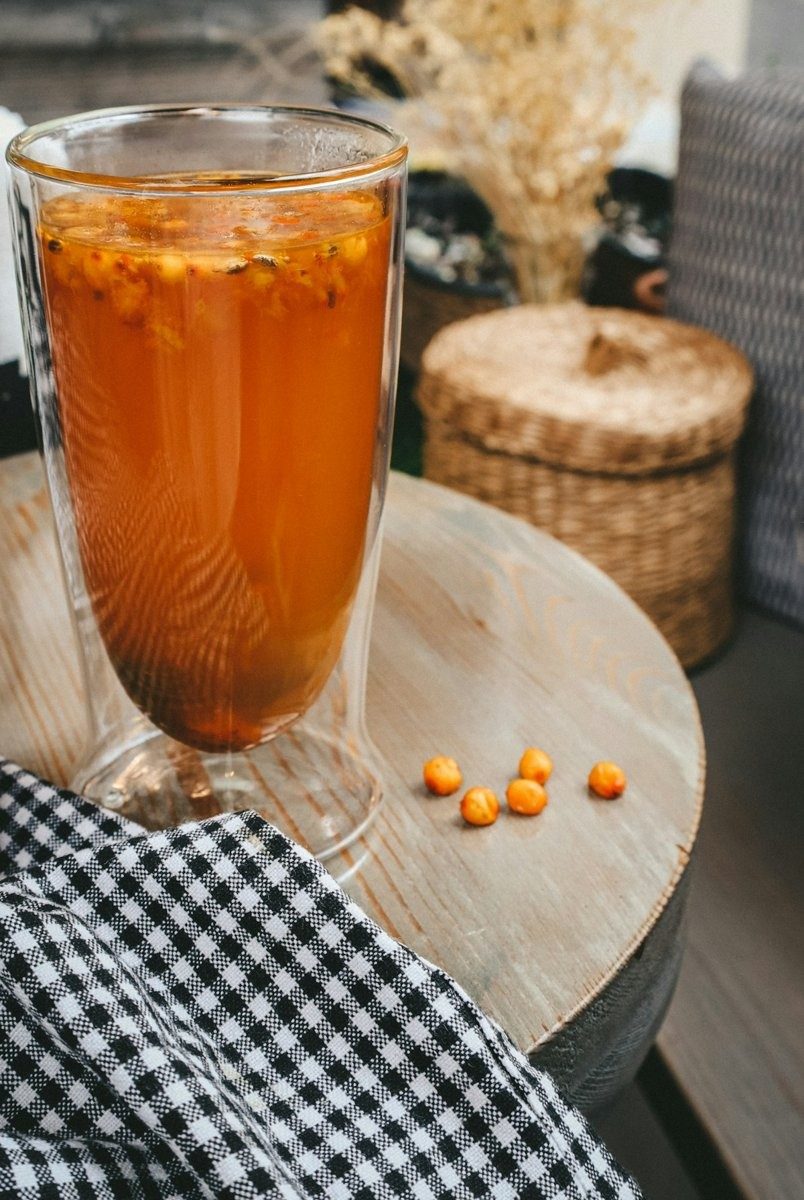 Grand verre de boisson à l'argousier, quelques baies sur la table